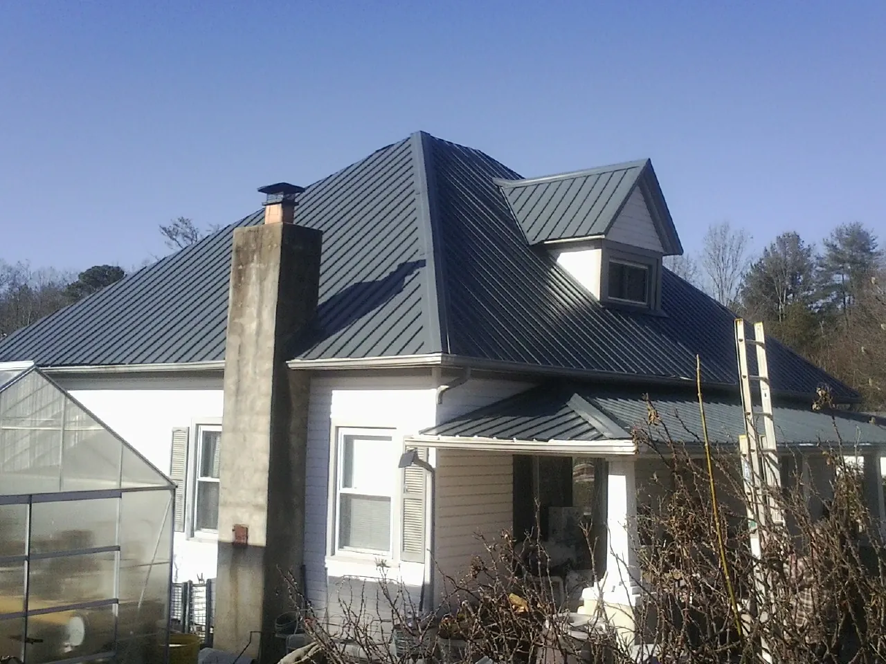 Dark blue standing seam metal roof on a white farmhouse with dormer — Slate & Tile Roof Repair by Roofing Brothers in Moxee