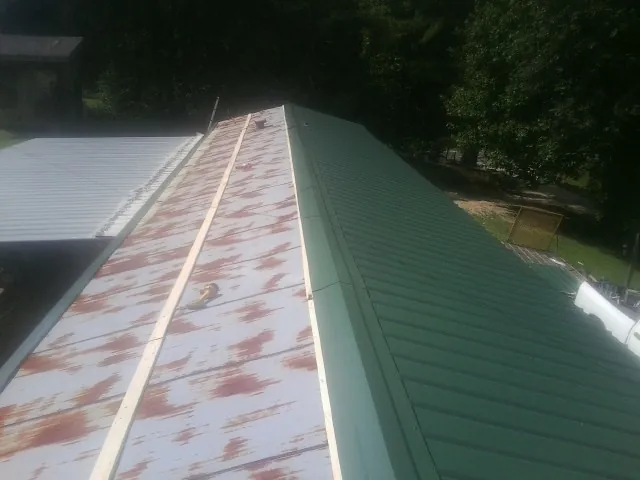 Old rusted panels beside newly installed green metal roofing — Wind Damage Roof Repair by Roofing Brothers in Moxee