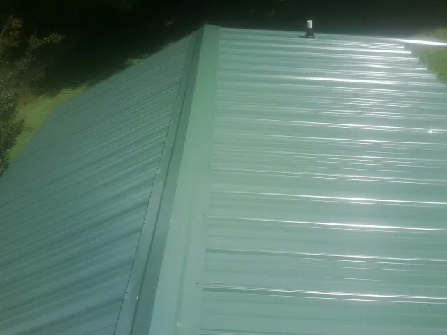 New green metal panels meeting at the ridge of a roof — Flat Roof Repair work by our crew in Moxee