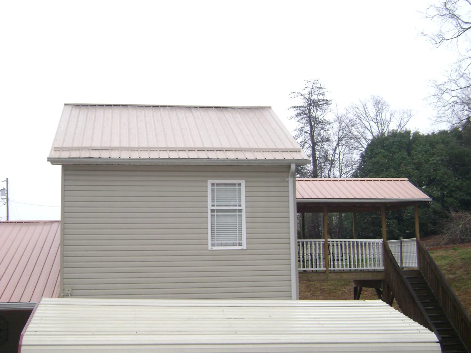 Tan metal roofs on a two story addition and attached porch, from a Roof Replacement job in Moxee