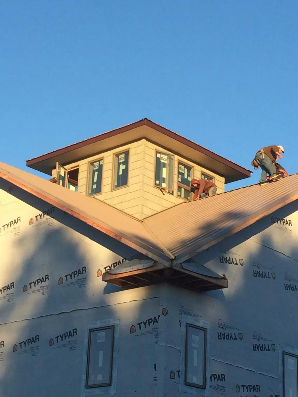 Roofers working around a rooftop cupola on a new metal roof at sunset — Roof Waterproofing in Moxee by Roofing Brothers